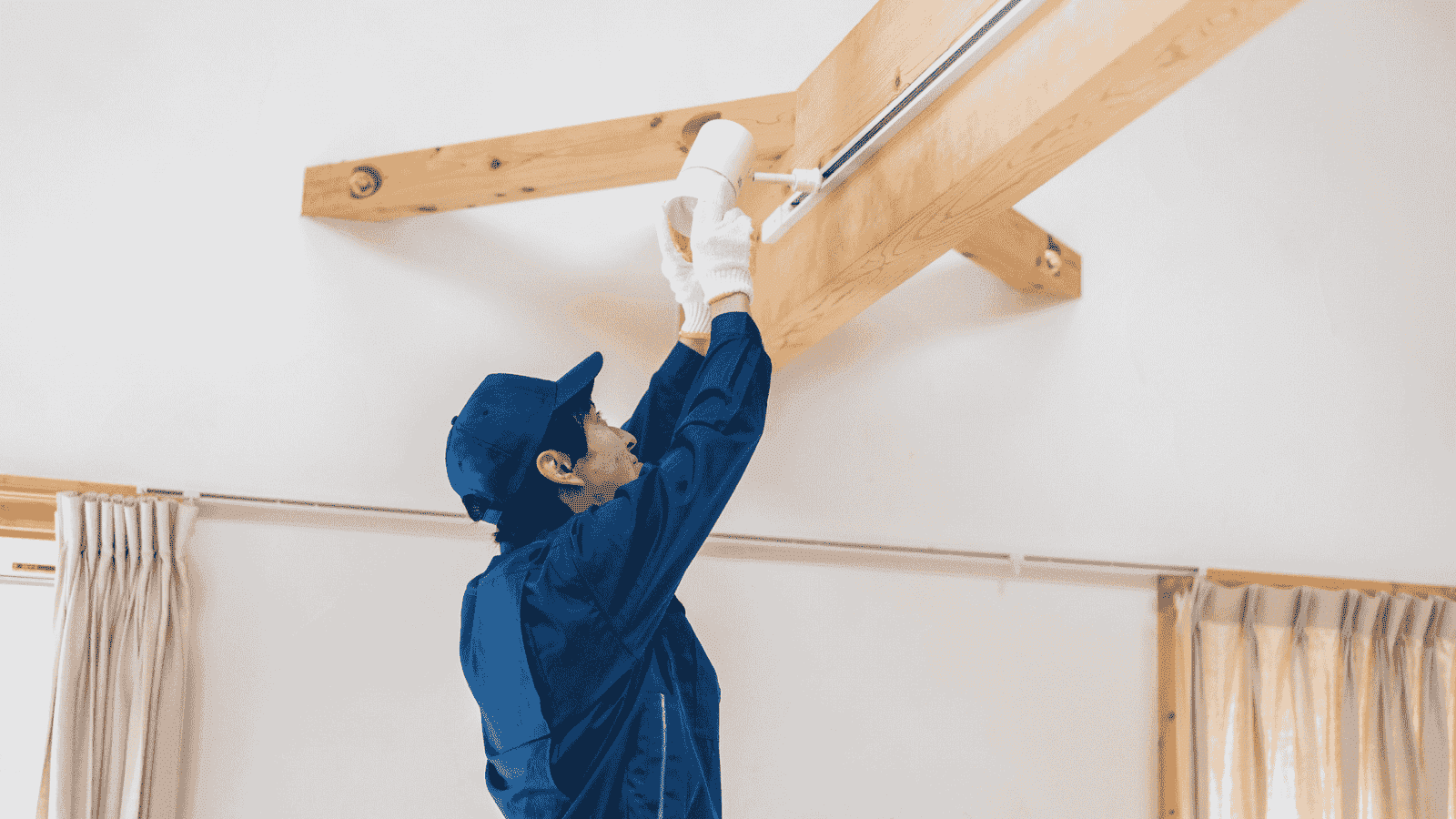 Electrician installing modern ceiling track lighting fixture indoors